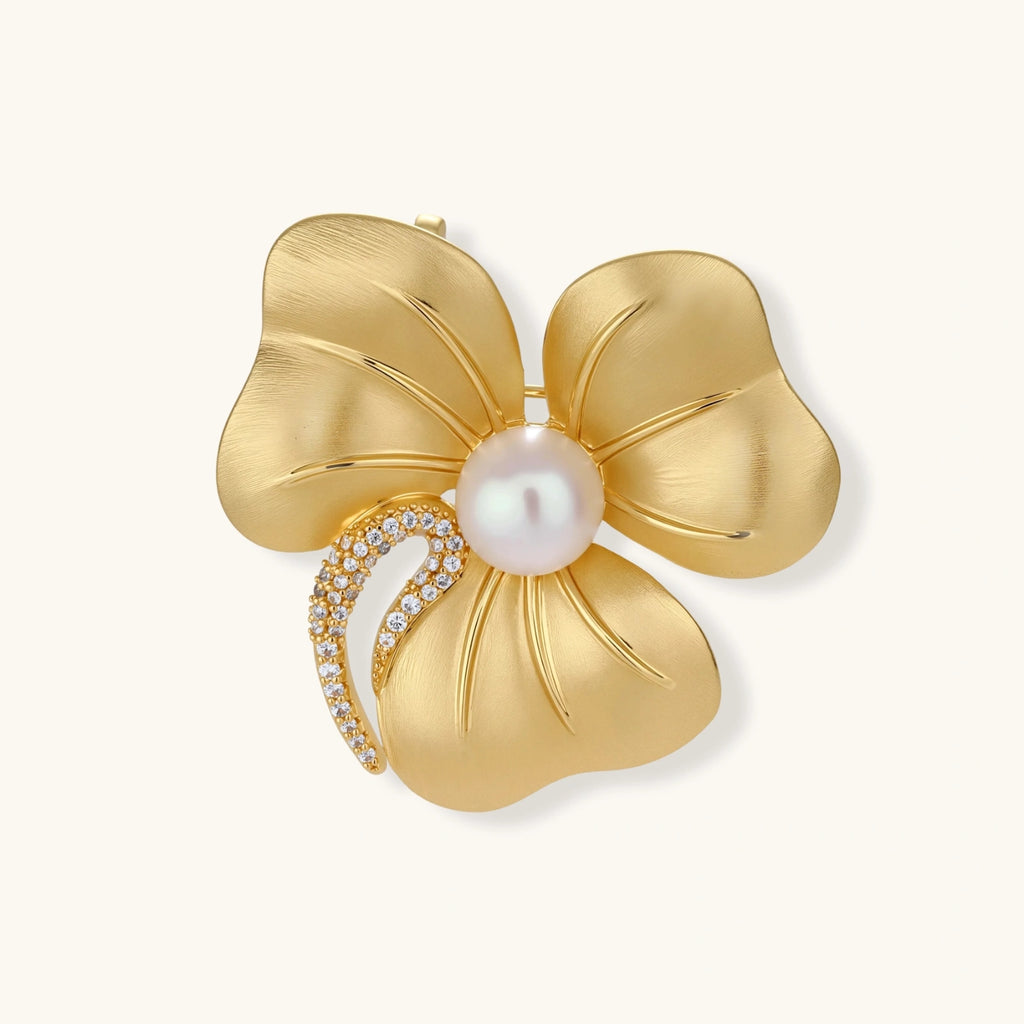 18K gold-plated copper flower brooch with five petals, white pearl center, and crystal stem accent on white background.
